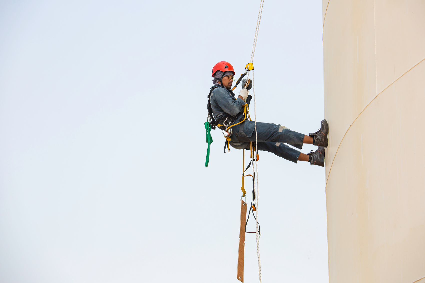 Male worker rope access industrial working at height tank oil we